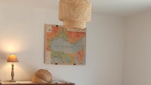 Un comedor con una mesa redonda, sillas de mimbre, un armario de madera y un mapa en la pared.