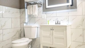 Un baño moderno con inodoro, tocador con espejo y barra para toallas.