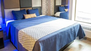 Una habitación de hotel moderna con una cama grande, una mesita de noche, un espejo y una ventana con vistas.