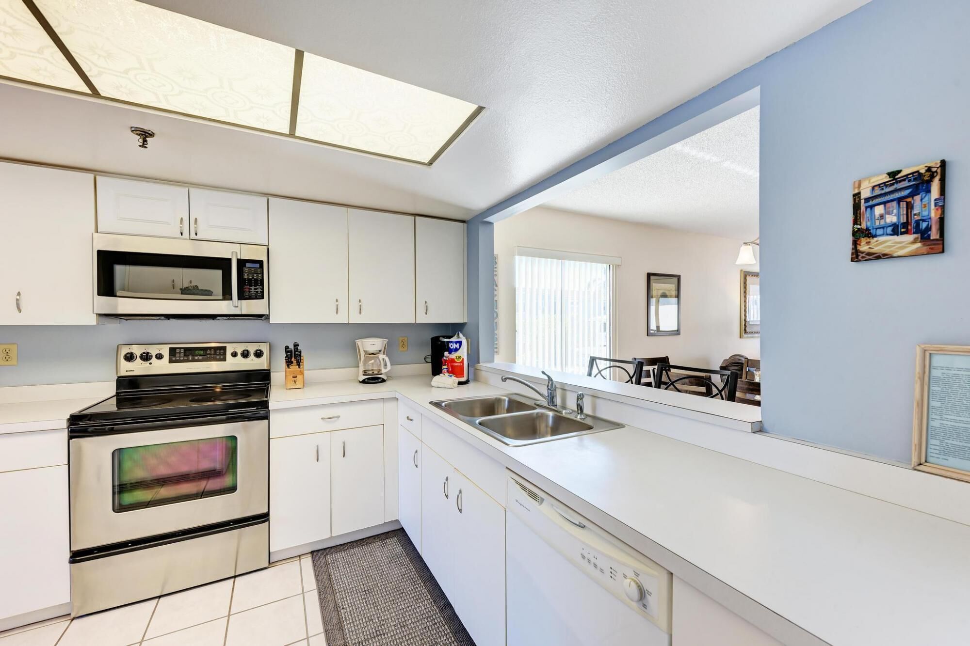 A compact kitchen with white cabinets, a microwave, a stove, and a dishwasher.