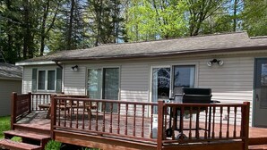 A mobile home with a wooden deck, a barbecue grill, and a patio table. - Quiet "UP NORTH" Cabin with all the Amenities. 200 a night. (Lakewood)