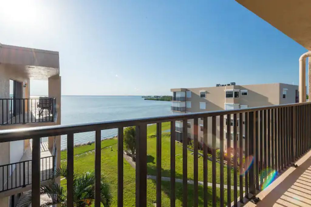 Ein Balkon mit Blick auf das Meer, eine Rasenfläche und ein Gebäude im modernen Stil.