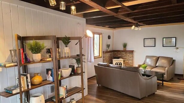 A living room with a wooden floor, a fireplace, a sofa, and a bookshelf. -  Carriage House in Old Saratoga (Schuylerville)
