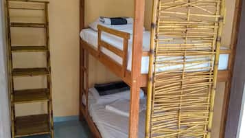 A bunk bed with a bamboo ladder and a wooden shelf unit.