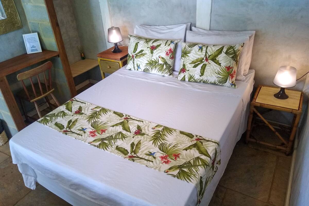 A bed with floral bedding, two bedside lamps, and a wooden nightstand.