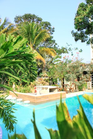 A pool area with palm trees and a wooden deck. - Jardim Secreto Guest House - Hostel (Búzios)
