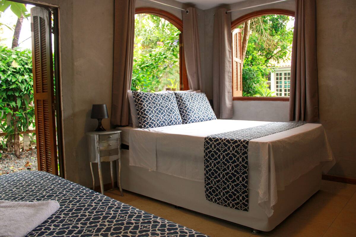 A bedroom with a bed, a nightstand, and a window with curtains.