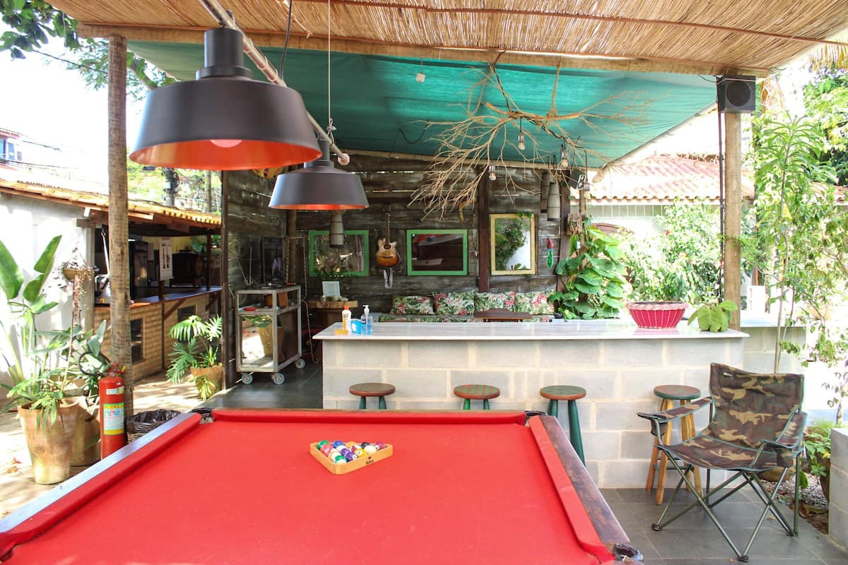 A pool table with a ball rack, a bar area with stools, and a seating area with a pool table.