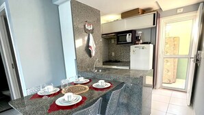 A modern kitchen with granite countertops, a built-in microwave, and a refrigerator. - Villas Do Atlântico (Ipojuca)