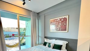 A modern hotel room with a large bed, a view of the outdoors, and a digital control panel on the wall. - Villas Do Atlântico (Ipojuca)