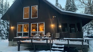 Eine zweistöckige Holzhütte mit Veranda und Sitzgelegenheiten im Freien.