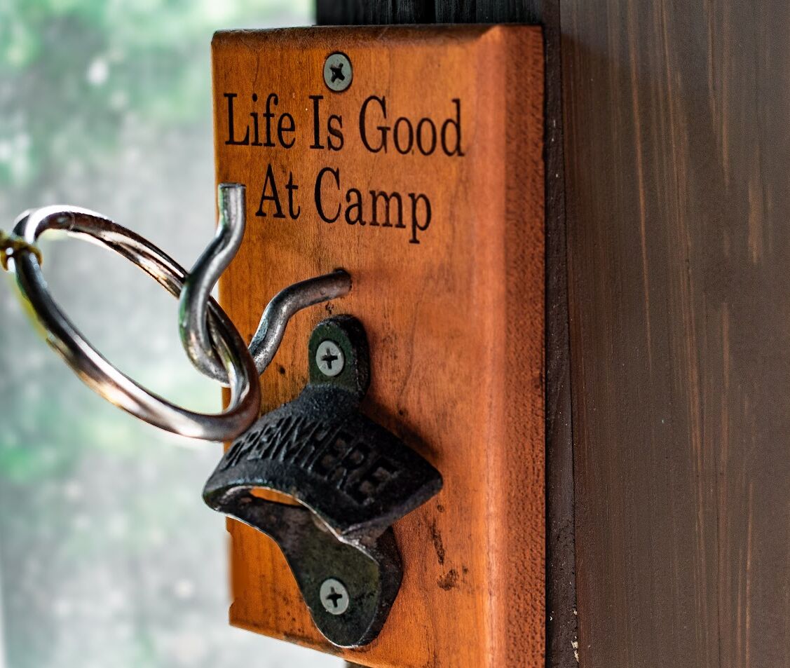 A wooden plaque with the text "Life Is Good At Camp" and a metal padlock attached to it.