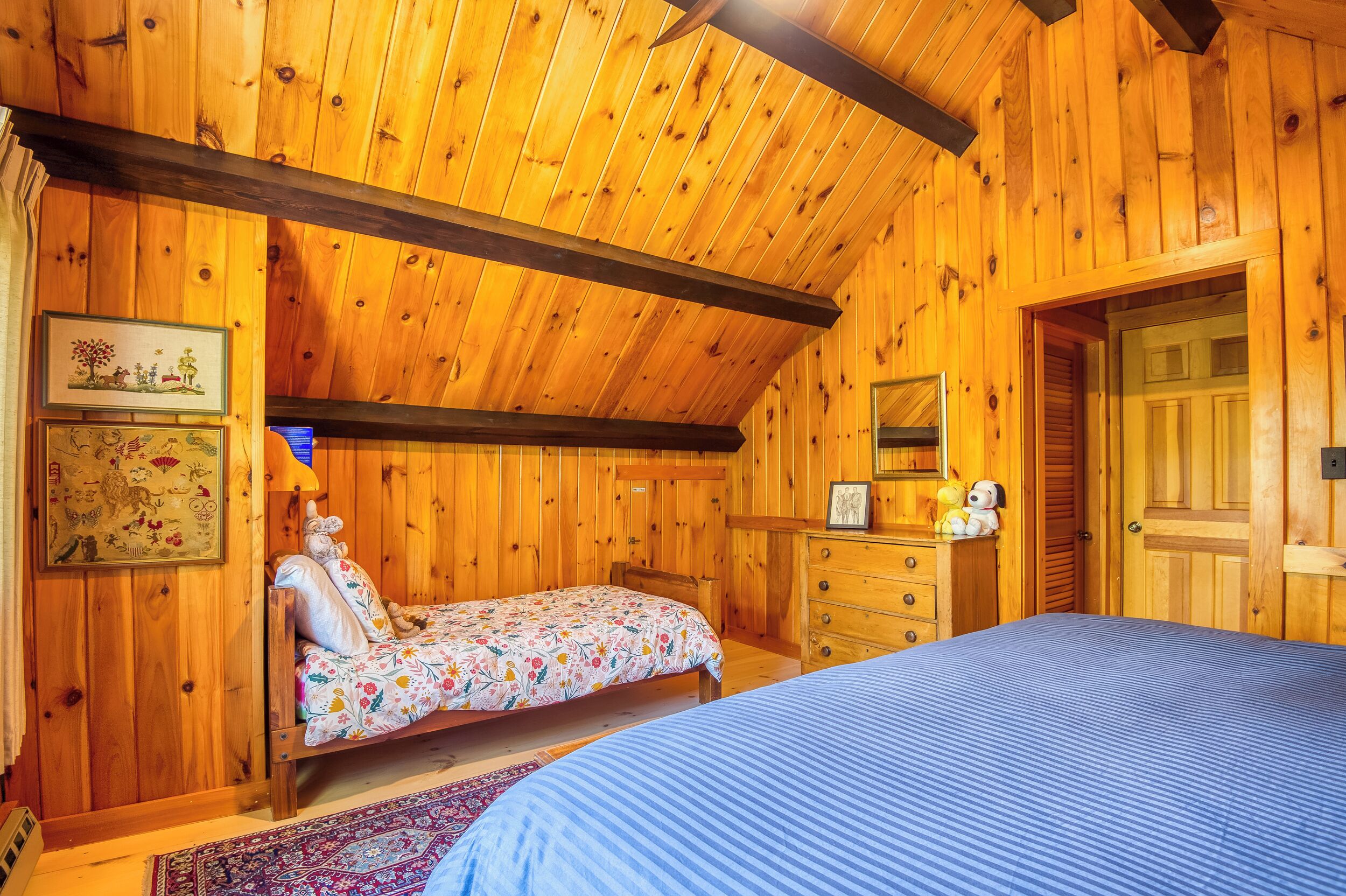 A wooden cabin bedroom with a bed, a dresser, and a mirror.