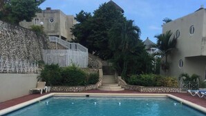 Una piscina con un muro de piedra y escalones que conducen a un edificio.