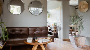 Una sala de estar acogedora con un sofá de cuero marrón, una mesa de centro de madera y una planta grande en maceta.