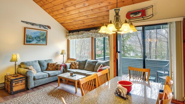 Un salon chaleureux avec un plafond en bois, un canapé, une table basse et un coin repas avec des chaises.