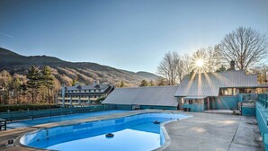Une piscine avec vue sur les montagnes et un bâtiment doté d’un toit en pente.