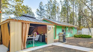 A small, rustic cabin with a green exterior and a wooden shed attached to it. - Grill, Fire Pit: Pet-Friendly Lakeside Cottage! (Lakeside)