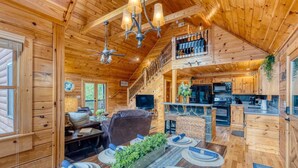A wooden cabin interior with a dining area, living room, and kitchen. - Mountain View Cabin - Hot Tub - Fire Pit - Pool Table - Game Room (Mineral Bluff)