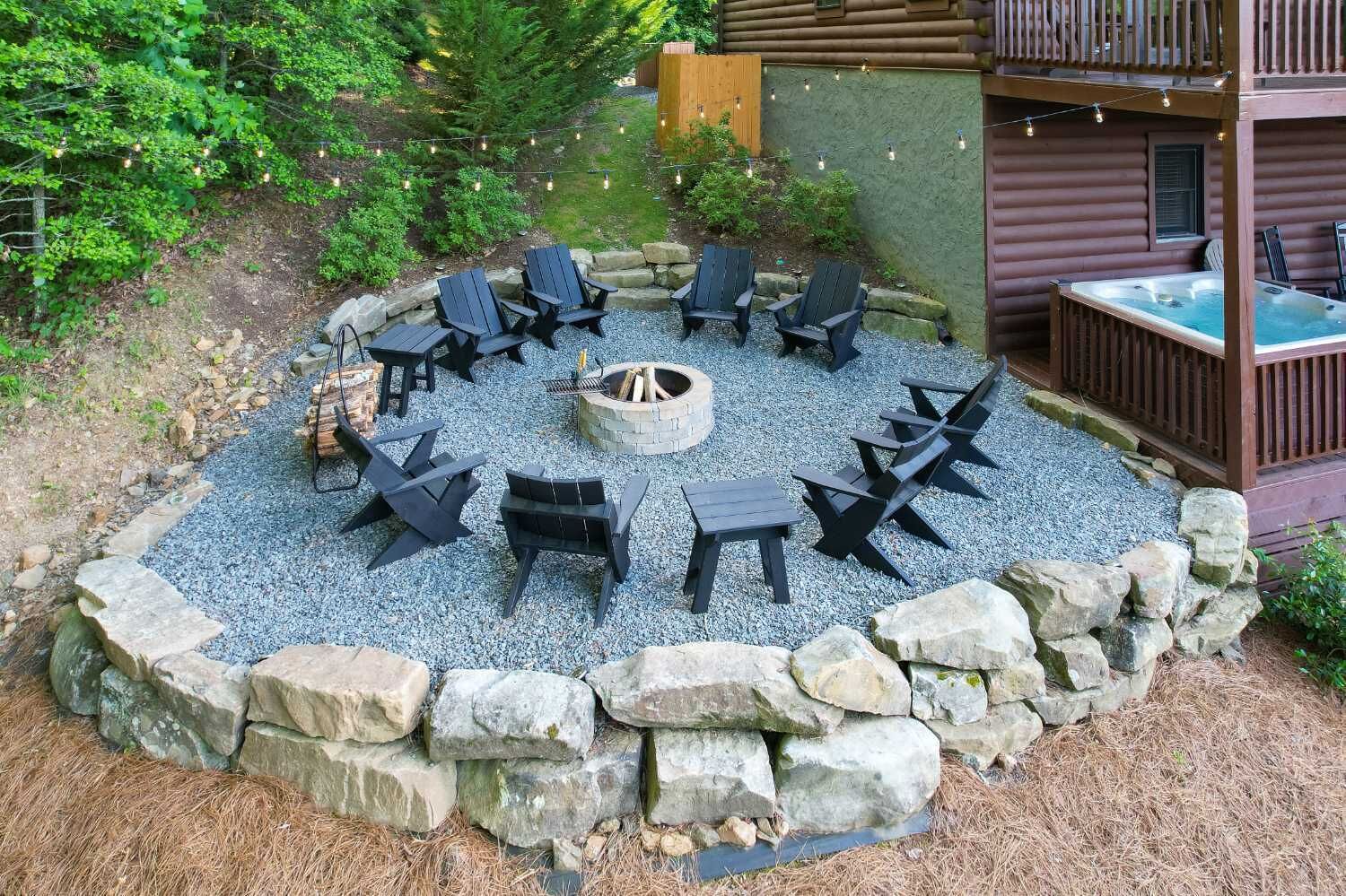 Un espacio de estar circular al aire libre con sillas Adirondack y un brasero, rodeado por un muro de piedra.