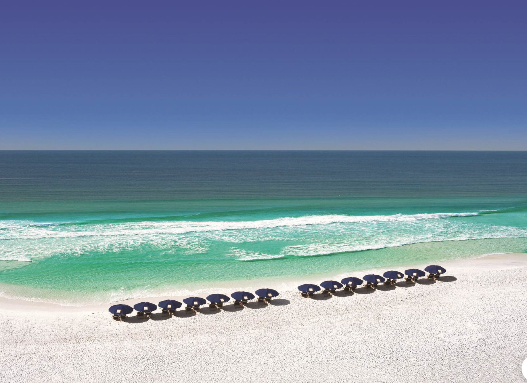 Ein Strand mit weißem Sand und klarem türkisblauem Wasser.