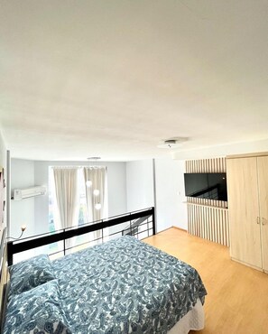 Une chambre à coucher avec un lit, une télévision et une armoire.