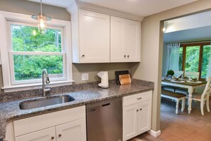 A kitchen with white cabinets, a granite countertop, a stainless steel sink, and a dishwasher. - Central AC 3 Min Walk to Pond! (Marstons Mills)