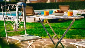 A metal chair and table set outdoors with a pool in the background. - Holiday apartment mit Pool und Klimaanlage (Mekiši kod Vižinade)