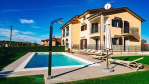 A two-story building with a swimming pool, outdoor seating, and a well-maintained lawn. - Holiday apartment mit Pool und Klimaanlage (Mekiši kod Vižinade)