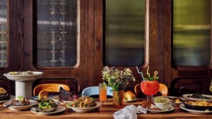 A dining table set with various dishes, drinks, and a vase of flowers. - Plum Perfect | Cozy SoCo Stay + Yard & Style (Austin)