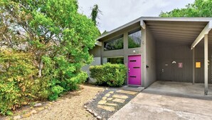 A modern building with a purple door, a covered garage, and a gravel pathway leading to the entrance. - Plum Perfect | Cozy SoCo Stay + Yard & Style (Austin)