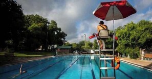 A swimming pool with a diving board and a lifeguard chair. - Plum Perfect | Cozy SoCo Stay + Yard & Style (Austin)