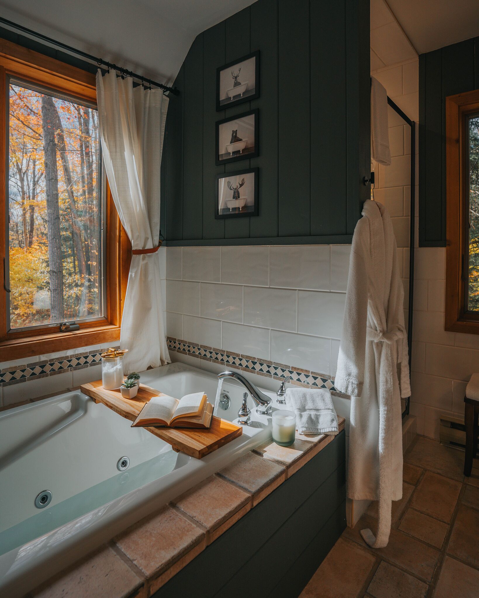 Une salle de bain avec une baignoire, une fenêtre avec des rideaux et des tableaux encadrés accrochés au mur.