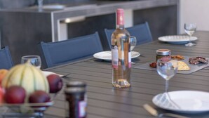 A dining table set with plates, a bottle of wine, a bowl of fruit, and a glass of water. - Villa Cupabia, sea view and heated pool (VIGGIANELLO)