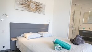 A neatly made bed with white linens, a grey headboard, and a teal towel on the side. - Villa Cupabia, sea view and heated pool (VIGGIANELLO)
