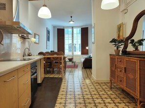 A kitchen with a dining area, a large window, and a wicker cabinet.
