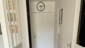 Een gang met een radiator, een houten tafel met een typmachine en een glas, en een deur met een ronde decoratie.
