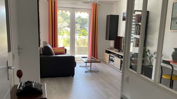 Een moderne woonkamer met een bank, een salontafel, een televisie en een schuifdeur die leidt naar een balkon.