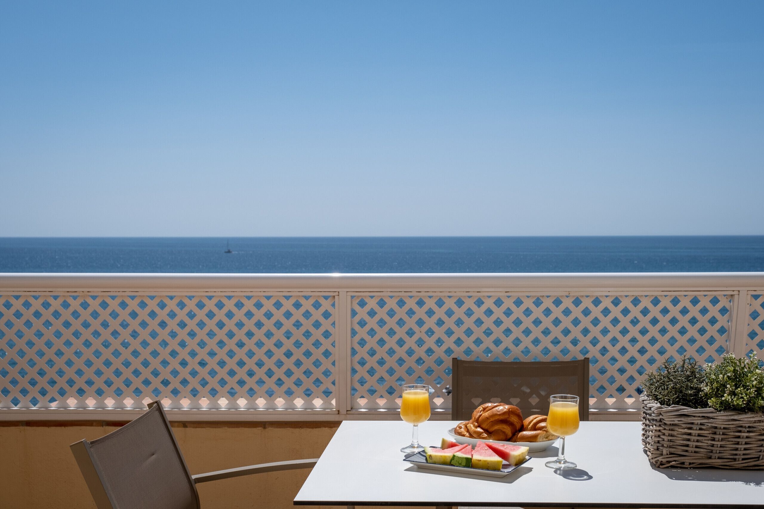 A table with breakfast items and a view of the sea.