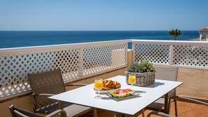 Een terras met een witte tafel, een rieten mand, croissant, watermeloen en glazen sinaasappelsap.