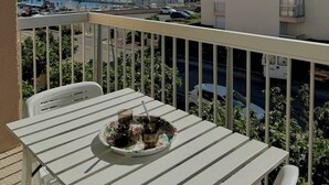 A balcony with a table set for two, overlooking a marina with boats and a building in the background. - Apartment with harbor and sea view 4PPII26 (LE BARCARES)