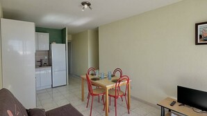 A compact living space with a dining area, kitchenette, and a TV on a wooden stand. - Apartment with harbor and sea view 4PPII26 (LE BARCARES)
