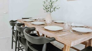 Une table à manger dressée avec des assiettes, des couverts et des verres, entourée de chaises noires.