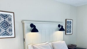 Quarto bem organizado com cama, duas mesas de cabeceira e luminárias de parede.