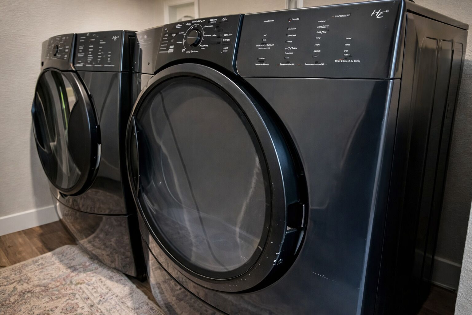 A front view of a black front-loading washing machine with a control panel and a large circular door.