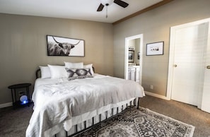 Une chambre à coucher avec un lit, un ventilateur de plafond, un tapis et un tableau accroché au mur.