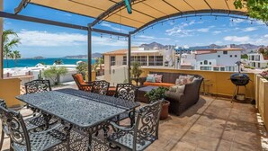 Un patio exterior techado con mesa y sillas, un sofá y una parrilla.
