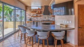 Una cocina moderna con una isla grande, taburetes de bar y vistas amplias a través de ventanas.