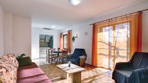 A living room with a sofa, a coffee table, and a dining area with chairs and a table. - Holiday apartment mit Terrasse und Klimaanlage (Medulin)