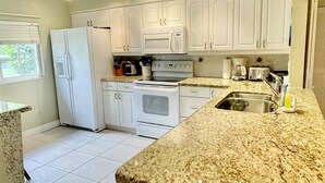 Eine Küche mit weißen Schränken, einer Granit Arbeitsplatte, einem Kühlschrank, einem Backofen und einer Spüle.